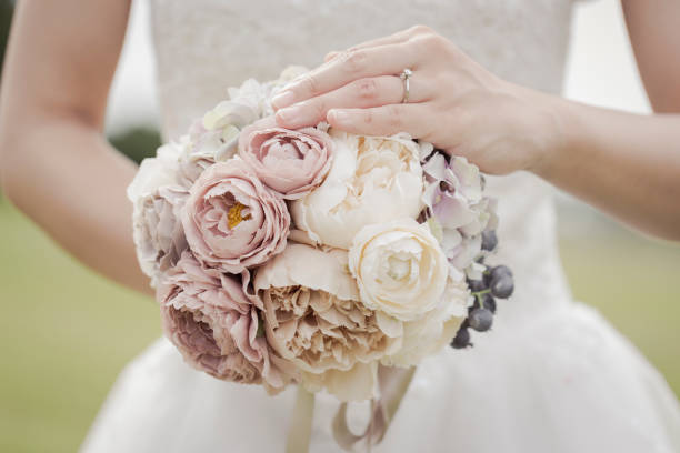 istock Bride holding a bouquet in the green field 1053299116