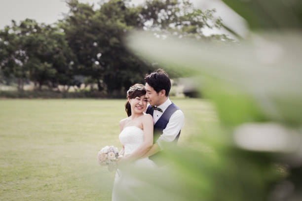 istock Groom embracing bride in the green field 1053299144
