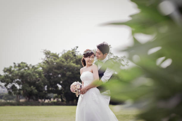 istock Groom embracing bride in the green field 1053299146