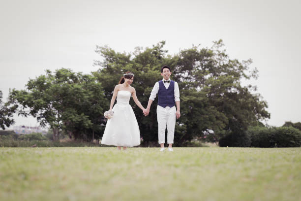 istock Bride and groom walking in the green field 1053299182