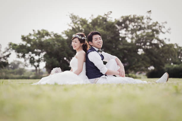 istock Bride and groom sitting in the green field 1053299212