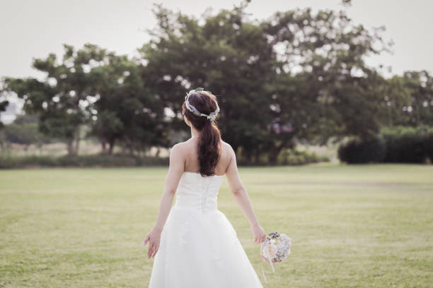 istock Bride holding a bouquet walking in the green field 1053299254