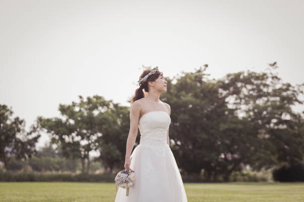 istock Bride holding a bouquet walking in the green field 1053299256