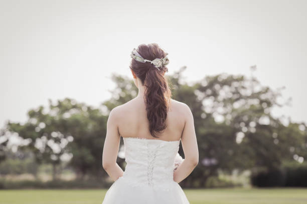 istock Bride holding a bouquet standing in the green field 1053299260