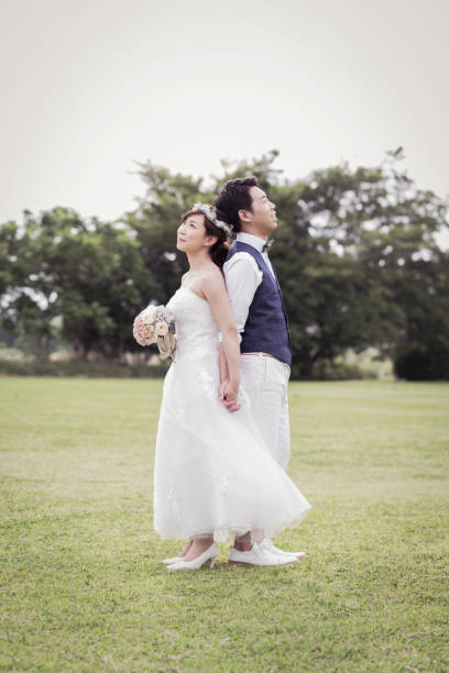 istock Bride and groom standing back to back in the green field 1053299270