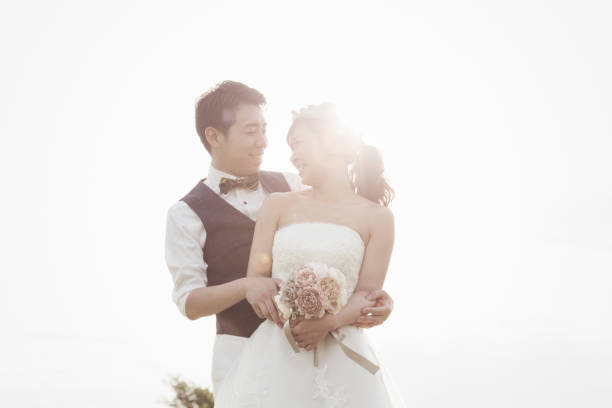 istock Groom embracing bride in the green field in backlight 1053299276