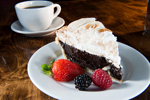 Chocolate Meringue Pie with Strawberry, Blackberry, Raspberry and Coffee Served on a White Plate