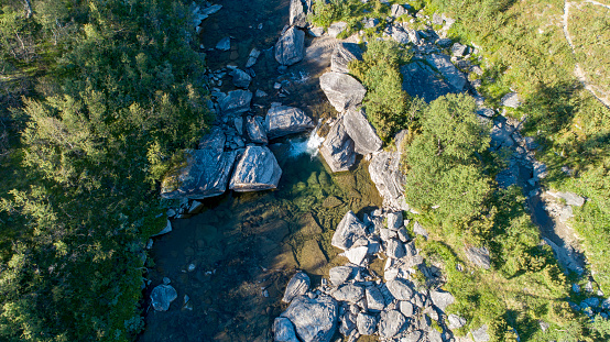 Aerial top view of a remote located canyon river in the middle of a summer green wild nature landscape, seen from high up from a drone.