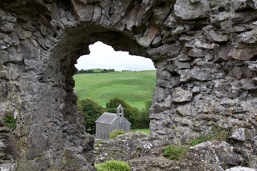 Medieval castle ruins in Ireland with view of a church in the window