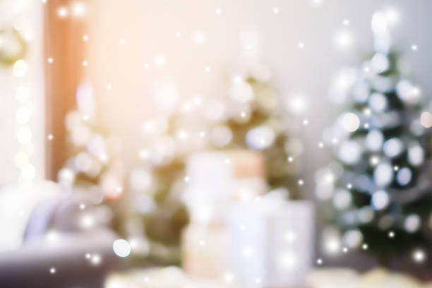 istock abstract blurred beautiful tree with ornate decoration inside sweet house background with snowfall effect for merry christmas and happy new year ; montage image or ads and banner design element 1053315956