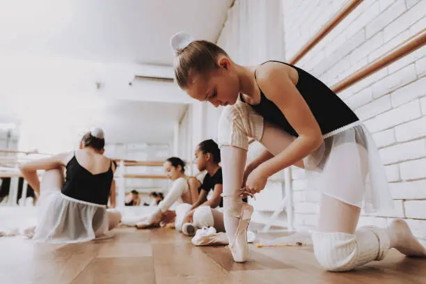 Young Girls Preparing for Ballet Training Indoors. Classical Ballet. Girl in Balerina Tutu. Training Indoor. Cute Dancers. Performance in Hall. Dancing Practice. Girls in White Dresses.