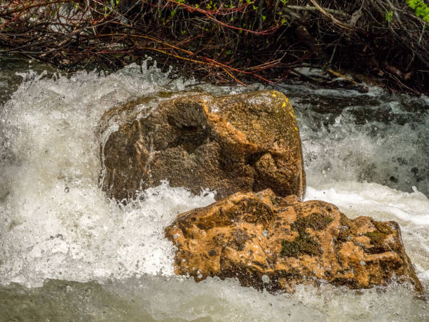 Two boulders surrounded by rushing water stock photo