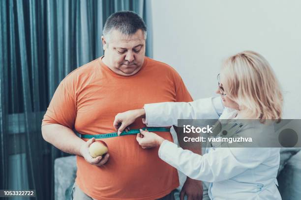 Fat Man With Doctor In White Coat In Gray Room Stock Photo - Download Image Now - Overweight, Doctor, Men