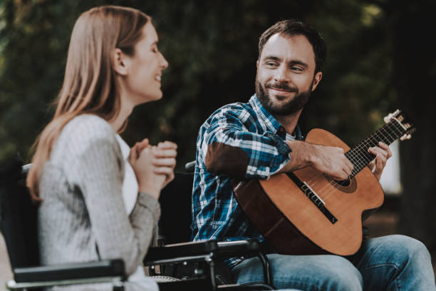 istock Disabled Man on Wheelchairs Playing Guitar in Park 1053323034