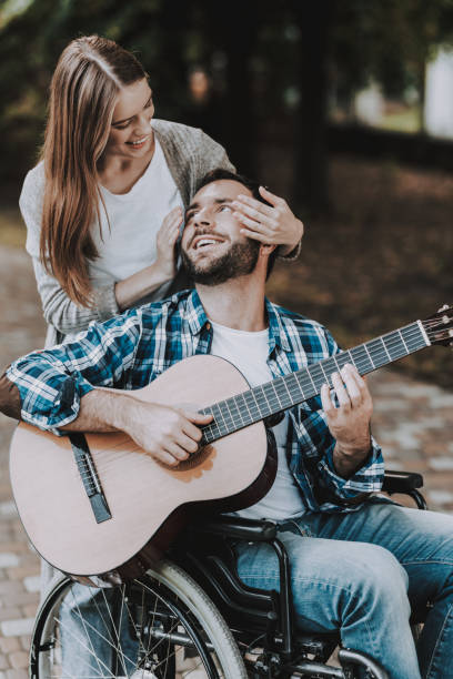 istock Disabled Man on Wheelchairs Playing Guitar in Park 1053323038
