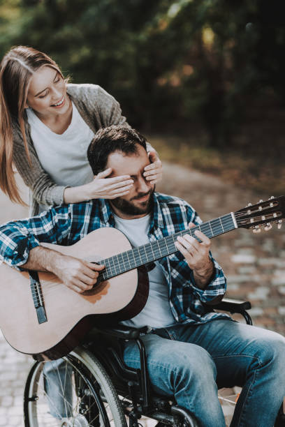 istock Disabled Man on Wheelchairs Playing Guitar in Park 1053323040