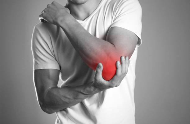 ein mann, hand in hand. schmerzen im ellbogen. der herd ist rot hervorgehoben. hautnah. isolierte hintergrund - shoulder pain physical injury muscular build stock-fotos und bilder