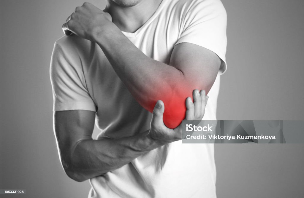 A man holding hands. Pain in the elbow. The hearth is highlighted in red. Close up. Isolated background A man holding hands. Pain in the elbow. The hearth is highlighted in red. Close up. Isolated background. Elbow Stock Photo