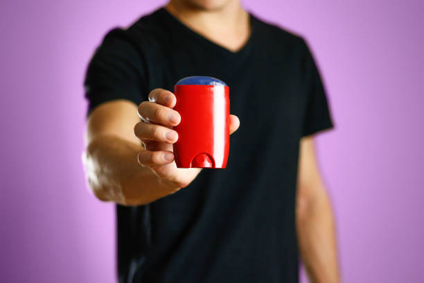 istock The guy is holding a red deodorant. Shows a deodorant. Close up 1053331072