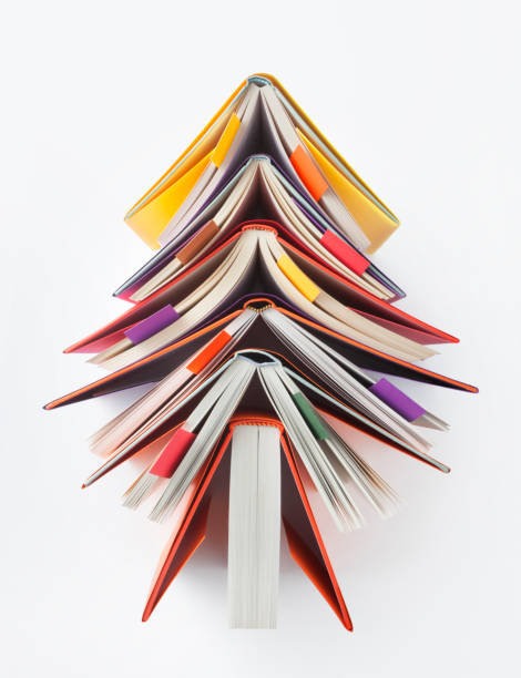 Christmas tree made out of books on white background.