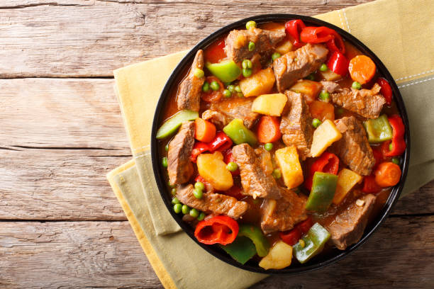istock Asian food: Stewed beef with potatoes, peppers, peas, tomatoes and carrots close-up on the table. horizontal top view 1053335726