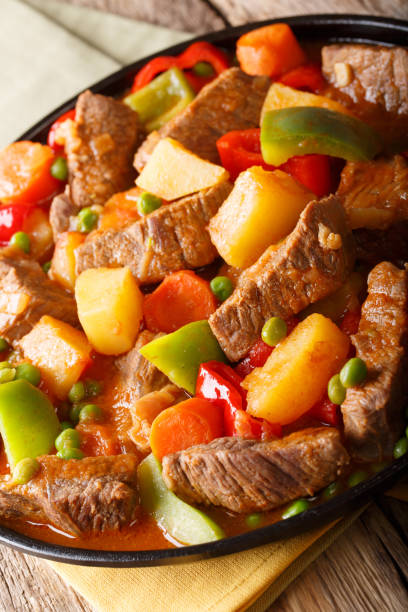istock Stew beef with potatoes, peppers, peas, tomatoes and carrots  closeup on a plate. vertical 1053335840