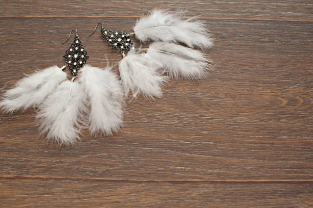 istock Beautiful delicate earrings with feathers on a wooden background. 1053343400