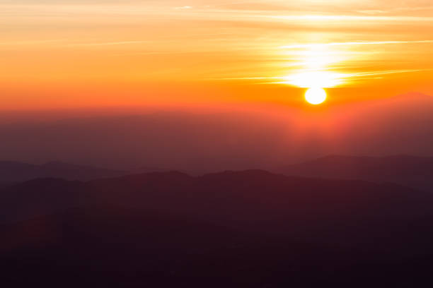 istock Beautiful sunset with sun coming down behind various layers of mountains 1053344046