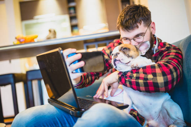 istock Handsome, hipster man sitting on the living room sofa with his dog, using laptop 1053347528