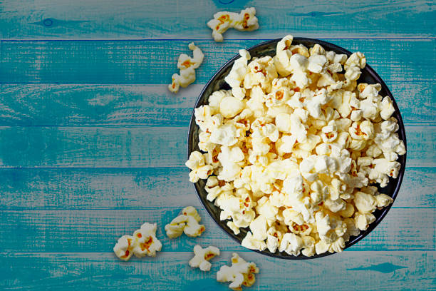 istock Corn popcorn on a blue wooden background with clipping path 1053376648