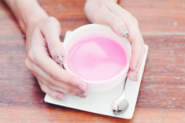istock Female hands with beautiful nails holding a white cup with pink tea. Creative concept. Purple color 1053382736