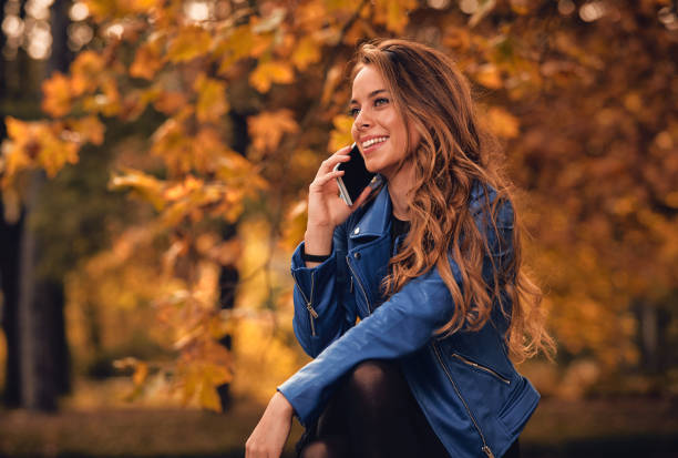 istock Cute girl using cellphone in park with autumn colors. 1053384550