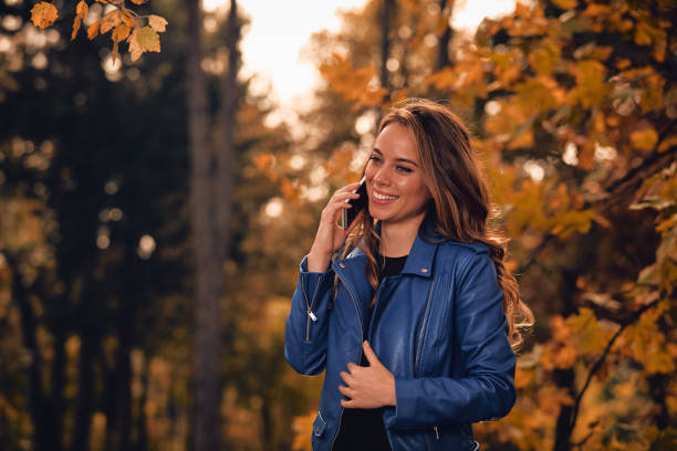 istock Cute girl using cellphone in park with autumn colors. 1053387922