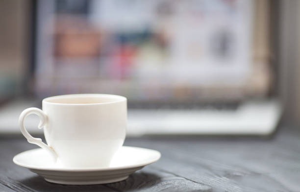 istock Coffee Cup on the black table on blurred laptop background 1053389312