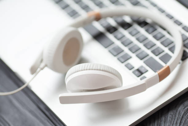 istock White headphone and laptop computer on wooden background. 1053389520