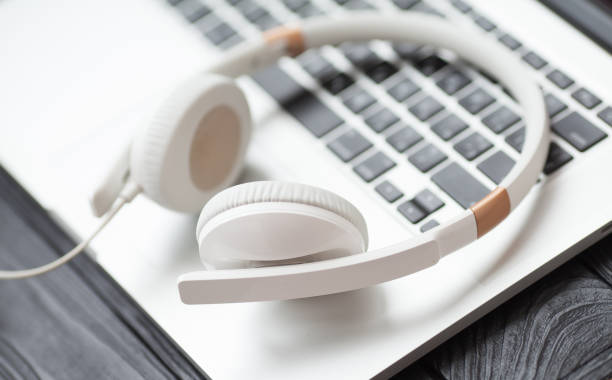 istock White headphone and laptop computer on wooden background. 1053389522