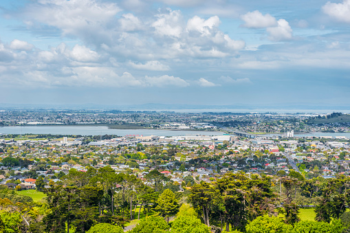 A view of Ohehunga suburb with the Mangere bridge in the background under a blue sky with clouds