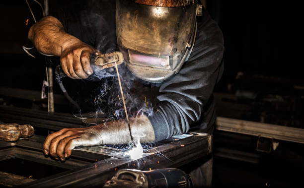 istock Professional welder in mask welds steel with electric torch tool 1053401662