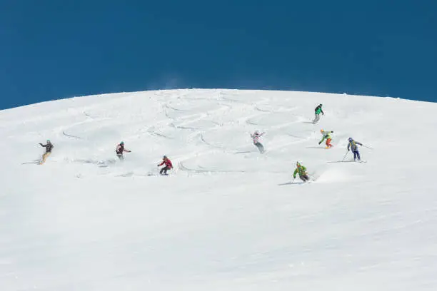 Group of friends skiing and snowboarding together in fresh powder snow
