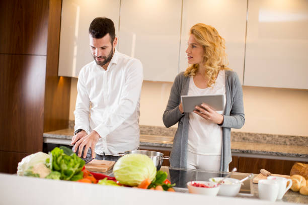 istock Loving couple standing in the kitchen  with digital tablet 1053411742