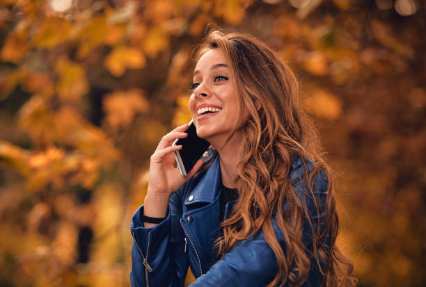istock Cute girl using cellphone in park with autumn colors. 1053412120