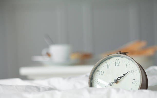 istock Breakfast time with black coffee, toast and clock on bed. 1053414186