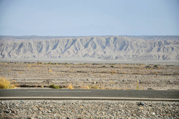 Long and lonely asphalt highway in southeastern Utah entering extreme terrain of cliffs and canyons. Miles and miles of straight highway with few curves through natural grasses and sage with no houses, building or man made structures. This is southeast corner of Utah in the United States of America (USA). Closest large cities are Phoenix, Arizona and Salt Lake City, Utah John Morrison Photographer