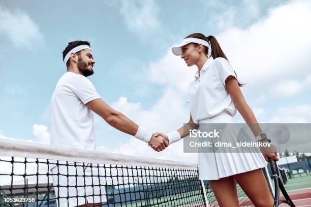 Shaking Hands After Good Game Man And Woman In Wristband Shaking Hands Upon The Tennis Net Stock Photo - Download Image Now