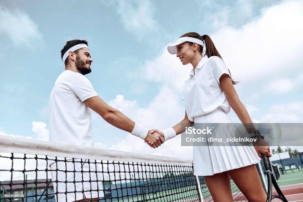 Apertando as mãos depois de bom jogo. Homem e mulher em pulseira apertando as mãos em cima do tênis - Foto de stock de Abstrato royalty-free