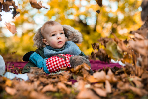 istock Cute baby boy enjoying in autumn falling leaves. 1053424832