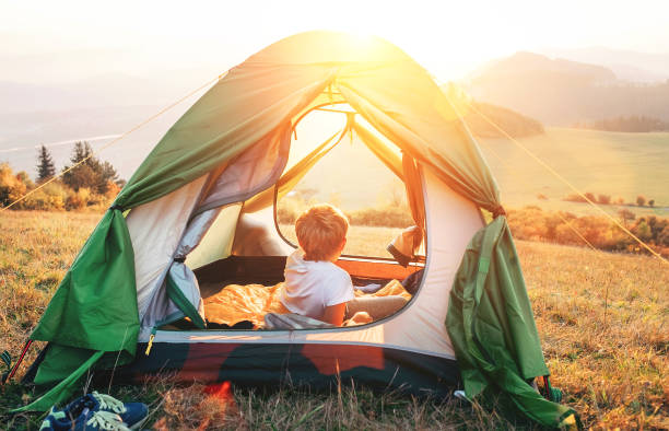 istock Boy rest in camping tent and enjoy with sunset light in mountain valley 1053426496