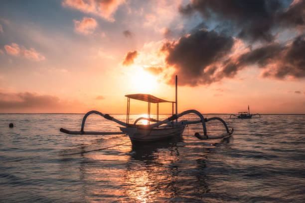 barco de pesca tradicional antigua de jukung a orilla del mar al amanecer colorido - jukung fotografías e imágenes de stock
