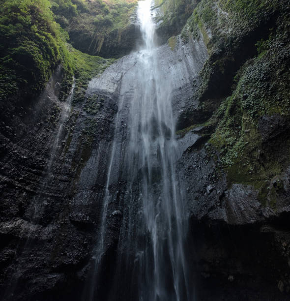 istock Majestic waterfall flowing on rocky cliff in tropical rainforest 1053426612
