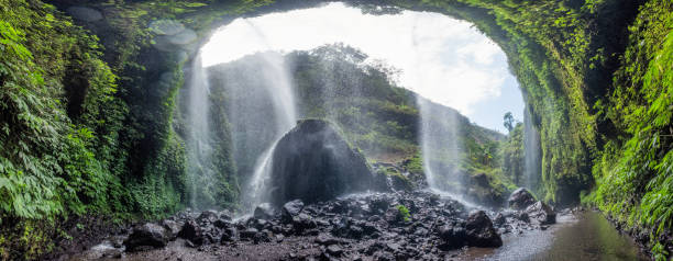 istock Majestic Madakaripura waterfall flowing on rocky cliff 1053426658